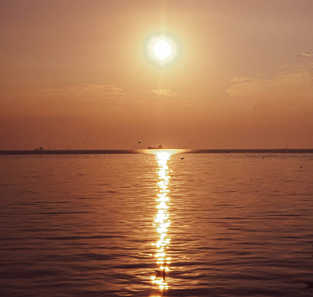istock Golden sun sets over tranquil sea, reflecting fiery path. 2249531384
