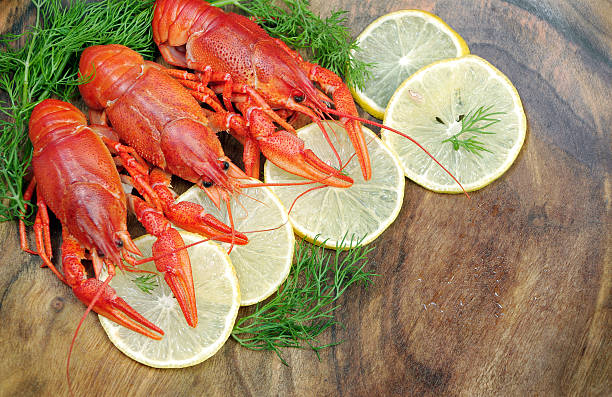 Many red boiled crayfish in a plate on the table with lemon slices.