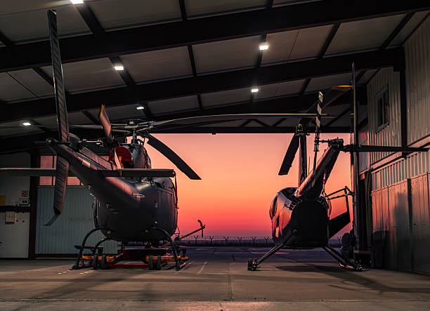 Helicopters parked in a hangar at sunset.