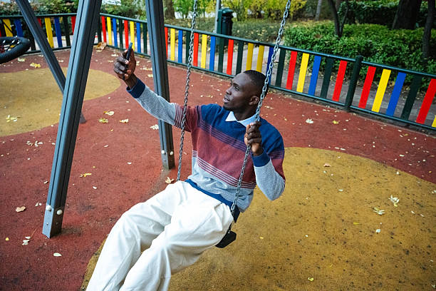 istock Man enjoying a sunny day in the park while taking a selfie on a swing 2249541339