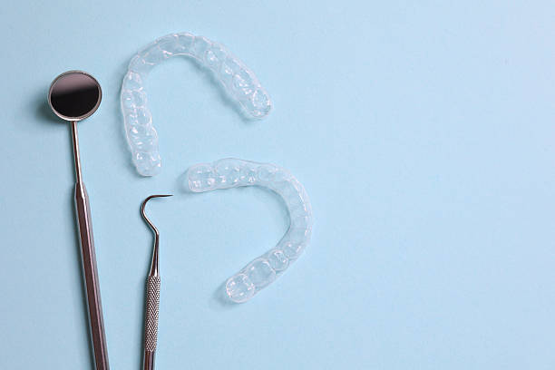 istock Transparent plastic aligners and dentist's tools on a colored background 2249546975