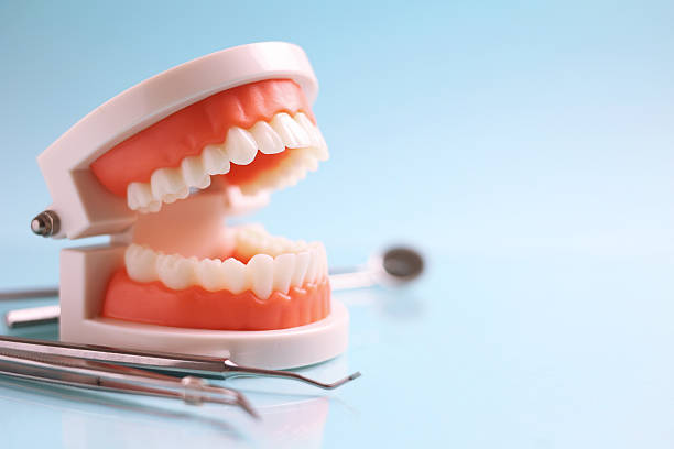 istock Dentist's tools and a dental model of teeth on a blue background close up 2249548356