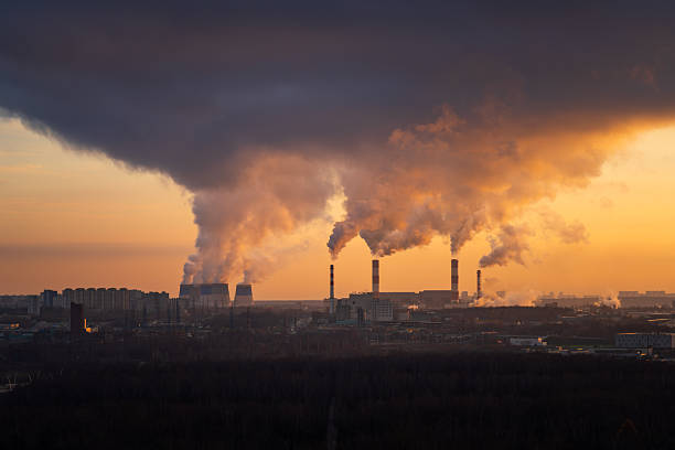 istock Industrial power plant smokestacks emitting smoke under dramatic dark cloud at sunset 2249550277