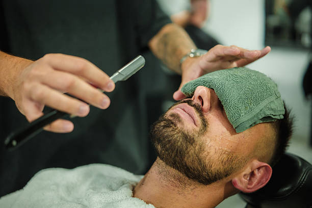 Man relaxing in barber chair receiving classic razor shave with hot towel