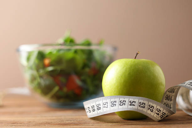 istock A Fresh Green Apple Placed Alongside a Measuring Tape Set Against an Aqua Background 2249555489