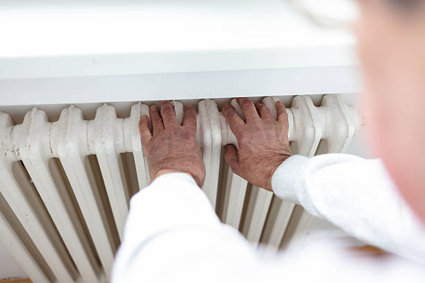 istock Man touches heating radiator indoors for checking the temperature. Heating system at home, concept. Man feeling cold at home having problems with home heating. 2249555717