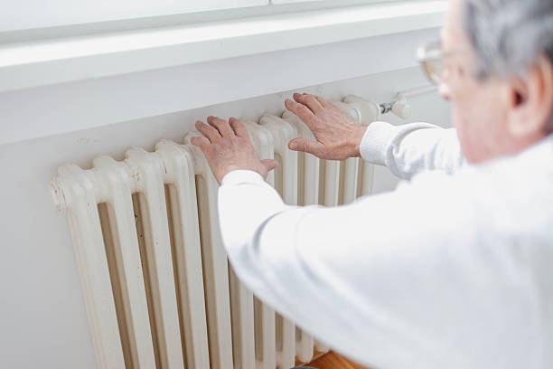 istock Man touches heating radiator indoors for checking the temperature. Heating system at home, concept. Man feeling cold at home having problems with home heating. 2249555799