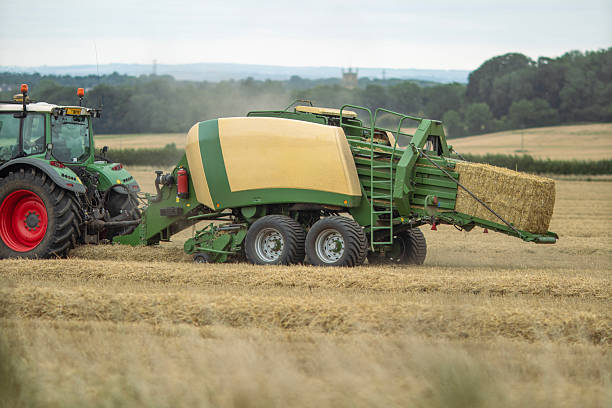 istock Straw Baling machine working in a field in the Cotswold landscape after the harvesting has been completed 2249556849