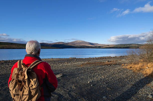 istock Senior man standing on the shore of a loch 2249556954