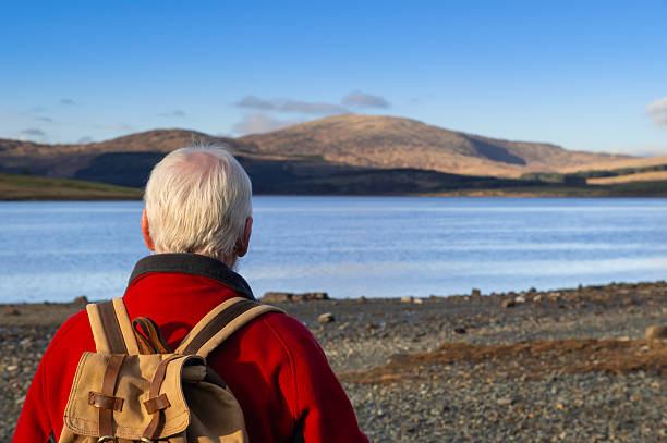 Senior man standing beside clatteringshaws loch in the galloway forest park in Scotland
