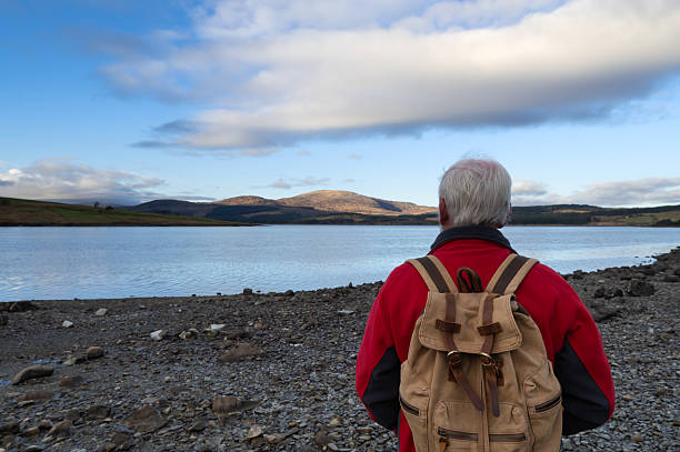 Retired man standing beside clatteringshaws loch in the galloway forest park in Scotland
