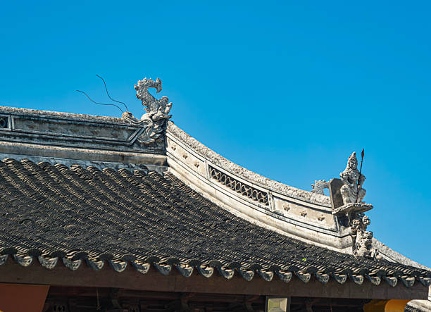 Traditional Asian architectural rooftop with intricate dragon ornamentation under clear blue sky.