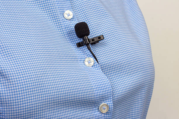 istock A compact black lav mic is secured on a white buttoned blue shirt, capturing the setup for professional audio recording. 2249559615