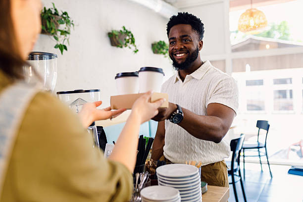 istock Smiling man taking a takeaway coffee from a barista in cafe. 2249562967