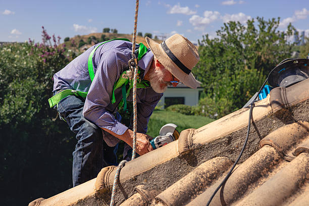 istock Senior man working on roof using power tool and safety harness 2249563110