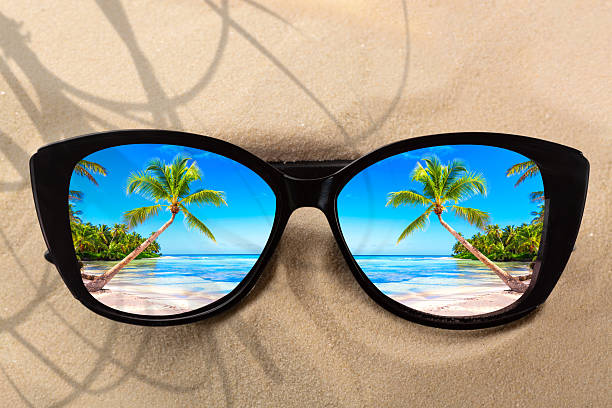 istock Summer vacation concept. Sunglasses on sand with ocean beach and palms reflection. 2249564684