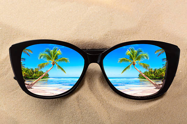 istock Summer vacation concept. Sunglasses on sand with ocean beach and palms reflection. 2249564691