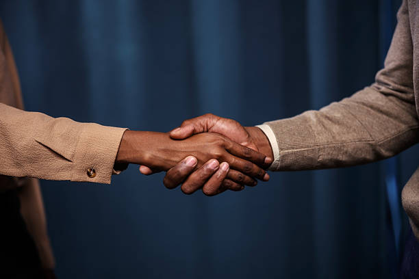 Seminar, professional and handshake of colleagues in agreement of trade show in workshop of company. Black people, man and woman together in meeting with audience for collaboration and teamwork