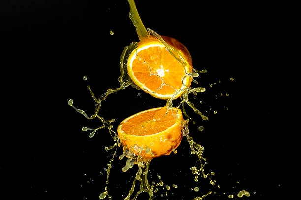 istock Fresh opened orange fruit with orange juice splashes on black background 2249567279