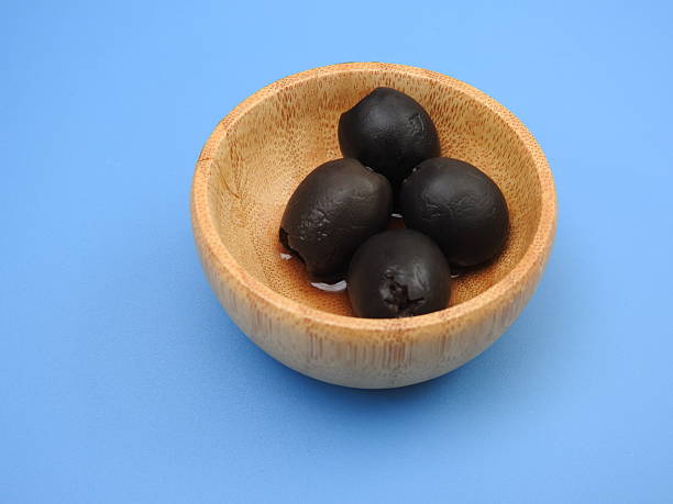 istock Set of black olives in wooden elements on a blue background 2249568875