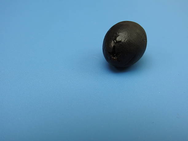istock A solitary black olive placed on a blue background 2249568889