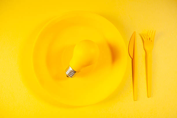 istock Yellow lightbulb and cutlery on a yellow background. 2249571430
