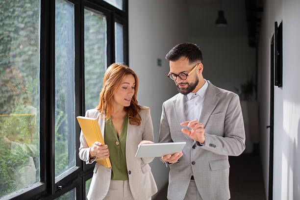 istock Colleagues using digital tablet discussing business in office corridor 2249571550