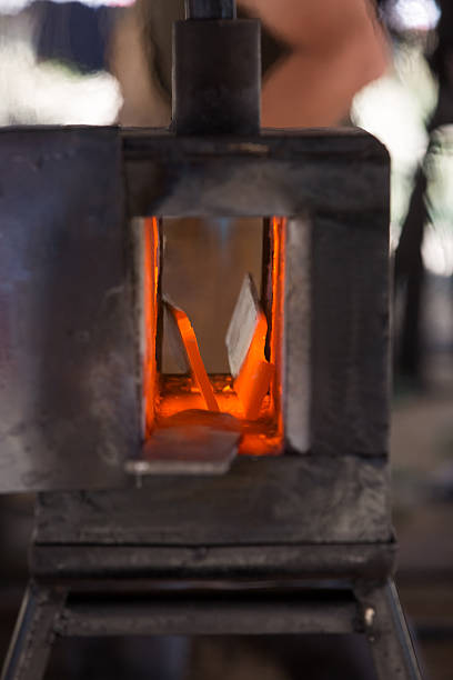 3 pieces of red-hot metal being heated in a gas forge to be forged into a knife