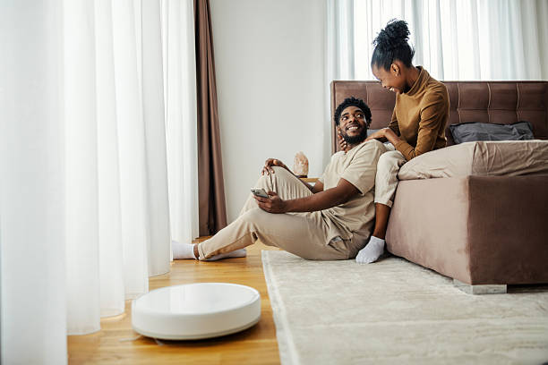 istock Black couple relaxing while robot vacuum cleaning bedroom 2249573683