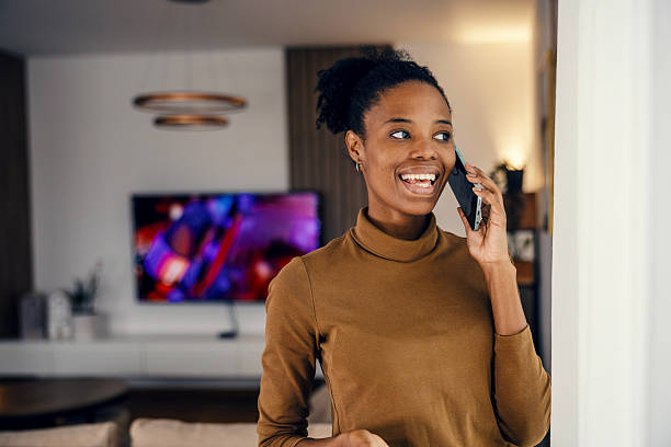 istock Happy young woman talking on mobile phone at home 2249575105