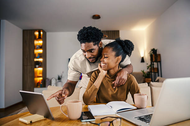 istock Black couple happily working together at home using technology 2249575733