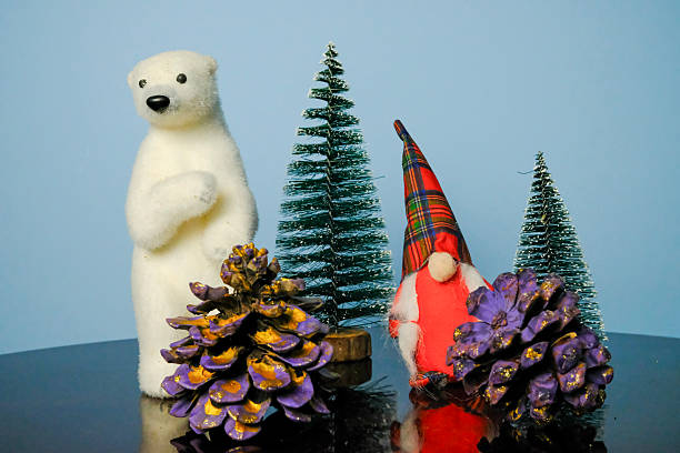 istock Christmas composition consisting of a polar bear, a gnome dressed in red, a small tree and pine cones decorated in shades of purple and gold 2249576371