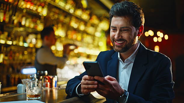 istock Laughing man chatting smartphone evening bar closeup. Guy scrolling cellphone 2249576397
