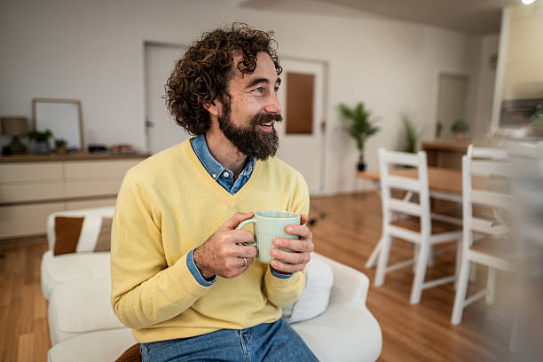 istock Smiling man relaxing with coffee mug at home 2249576927