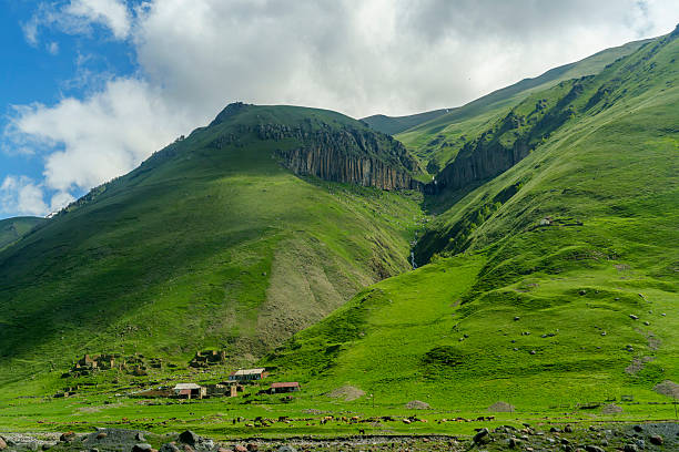 istock Remote green Caucasus valley with small farm beneath rocky cliffs 2249577904