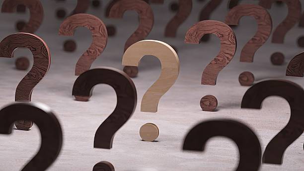 istock Numerous wooden question marks rotating and moving on a textured surface. With a shallow depth of field focusing on a single light-colored symbol. Representing doubt. Uncertainty. And seeking answers 2249578208