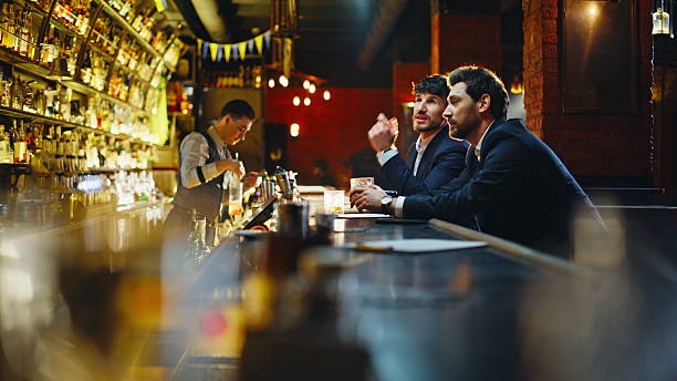 istock Bar visitors choosing drinks at counter closeup. Two friends ordering cocktails 2249578419