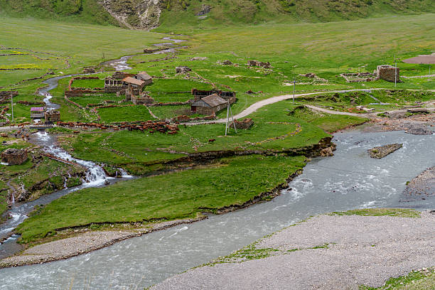 istock Waterfalls and hamlet above eroded riverbank in remote mountain valley 2249578947