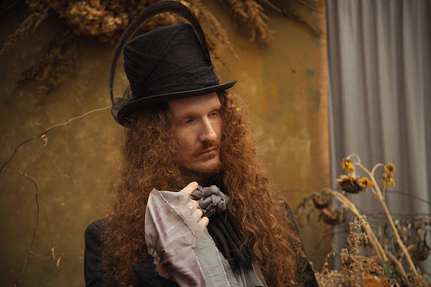 Gothic man with long hair in glasses and hat. Black classic clothes. Vampire in black suit. Halloween costume. Portrait