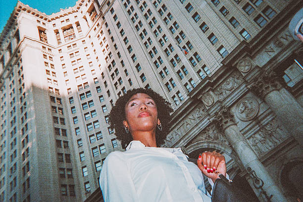 A dramatic low-angle shot captures several tall buildings rising into the sky, emphasizing the scale and density of New York City's architecture. The upward perspective conveys the iconic feeling of standing among massive city structures.Shot with a disposable point and shoot camera.