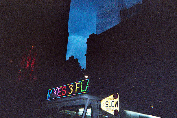 Dramatic nighttime alleyway scene showing building silhouettes and a lone illuminated window