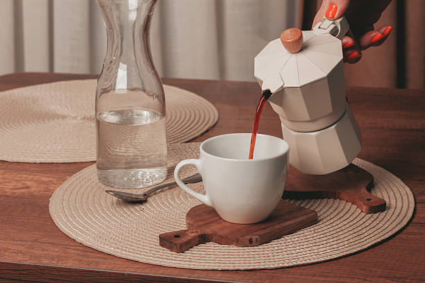 istock Coffee brewing in a cozy setting with a glass water pitcher and white cup on a wooden table 2249594406