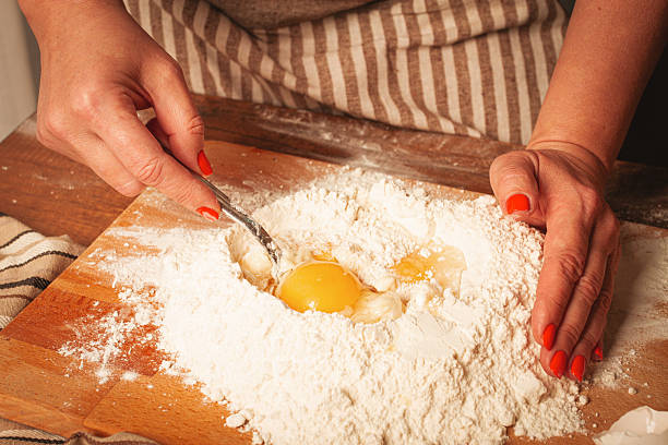 istock Hands mixing eggs into flour on wooden surface for baking at home kitchen during bright day 2249594518