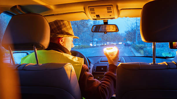Driver holding a v16 emergency beacon in car during roadside breakdown at night