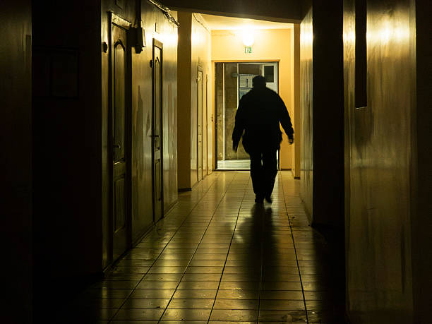 istock Person walking along dark, empty corridor leading to light 2249595761