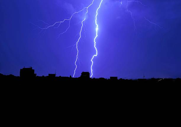 Lightning striking to the ground with a cityscape at night