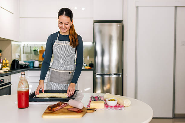 istock Young woman placing pizza dough in baking tray 2249601907