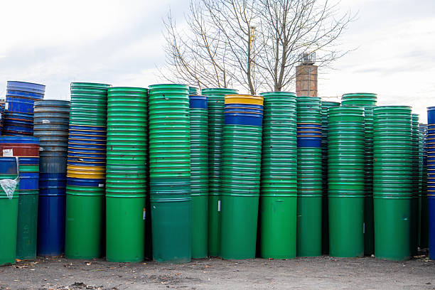Colorful barrels are neatly stacked in an open storage space under a cloudy sky, creating a striking visual contrast.