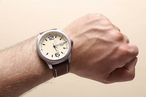 istock Men's wristwatch on the wrist, beige background 2249607163