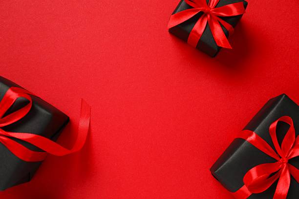 istock Festive gift box tied with bow on red background 2249610194